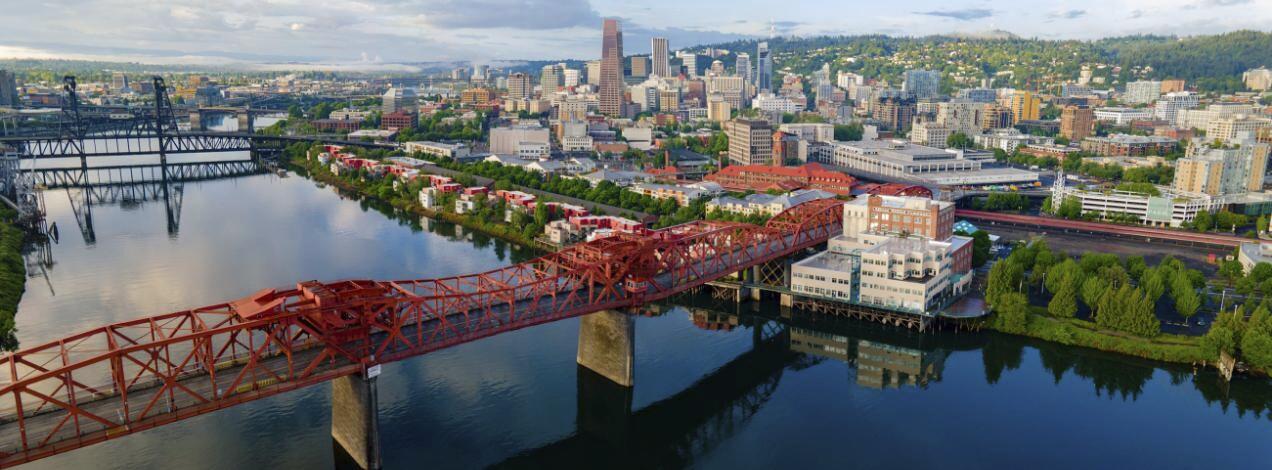 Portland's red Broadway Bridge spanning the Willamette River with the downtown skyline behind it.