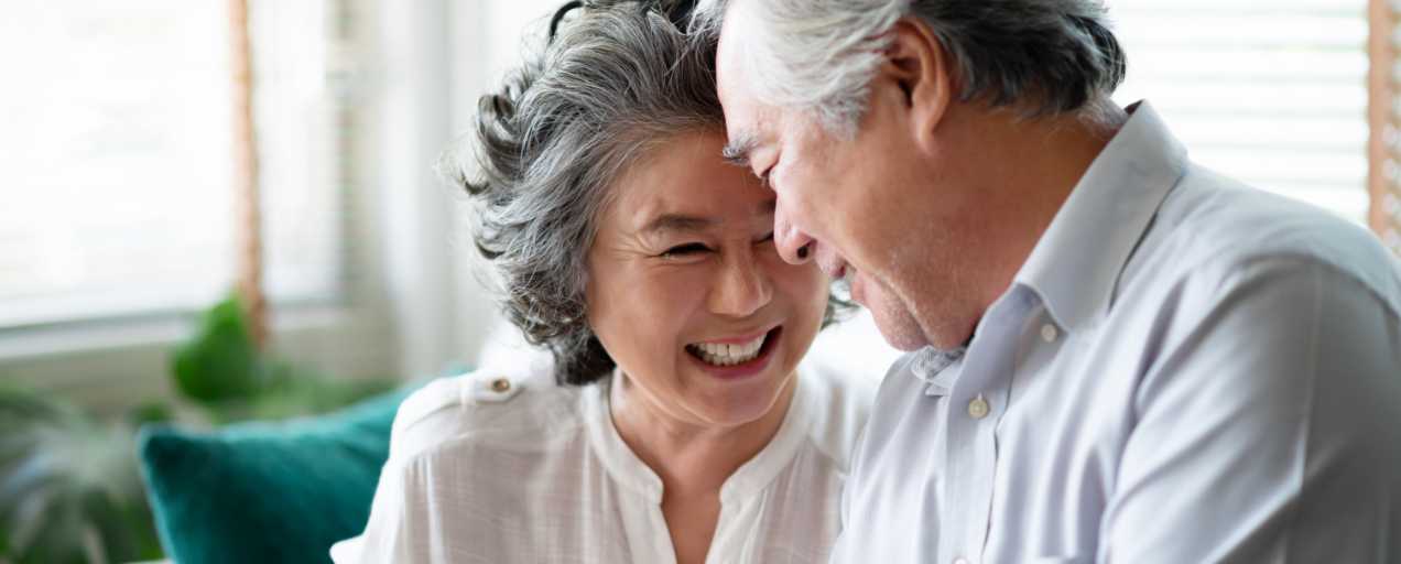 A smiling couple on a couch that now understands what Medicare is.