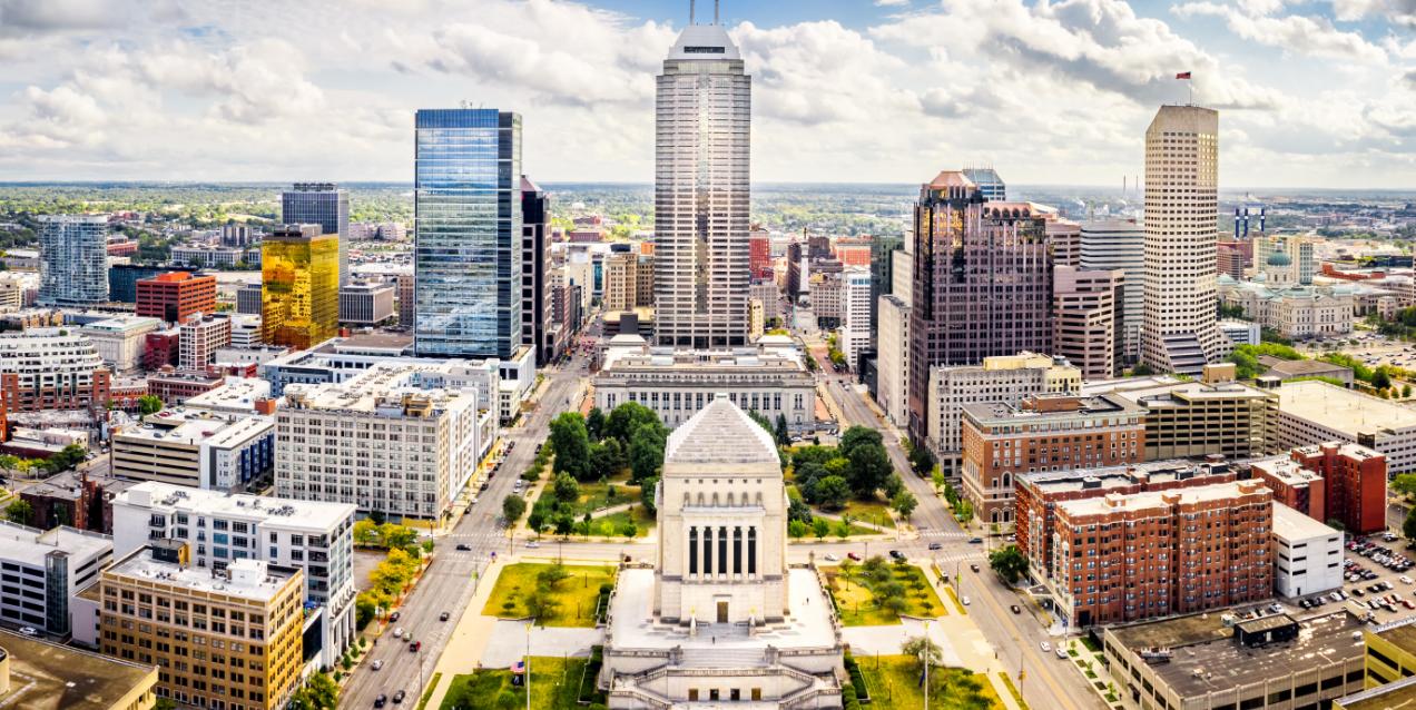 Aerial view of downtown Indianapolis, Indiana, with the Indiana World War Memorial in the foreground and skyscrapers behind it.
