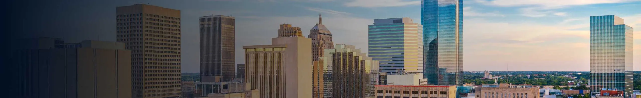 Oklahoma City skyline at sunset featuring the glass Devon Energy Center tower.