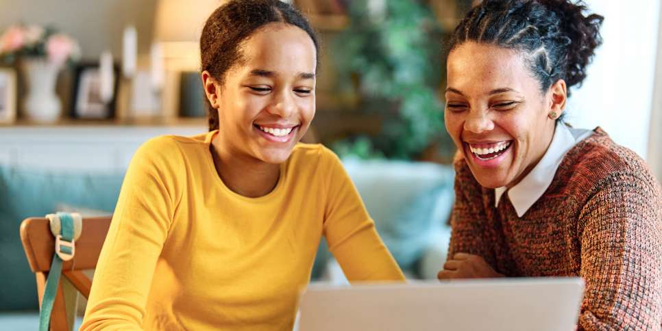 A Client Advocate and a woman laughing while looking at a laptop together.