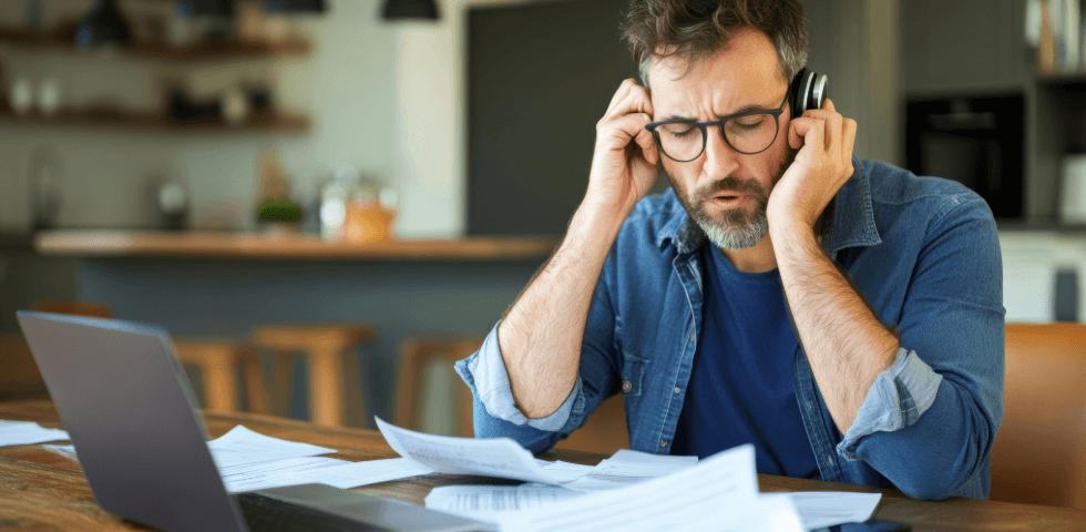 Frustrated man on the phone looking at a stack of papers