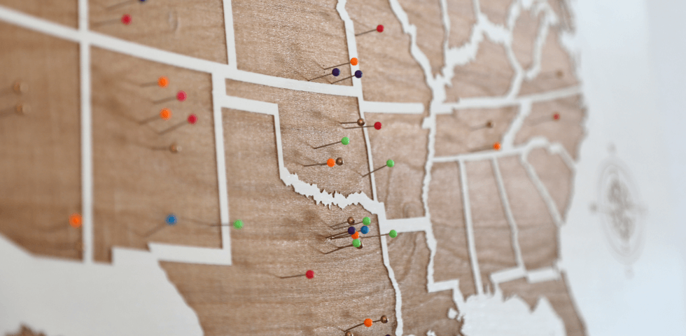 Corkboard map of the United States with colorful push pins marking large cities